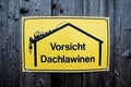 Yellow sign with warning of roof avalanches