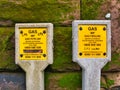 Yellow signs on concrete posts warn of Medium Pressure MP gas pipelines in an urban area in the north west UK