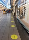 Yellow signs on the floor of a supermarket, keep 1 meter distance