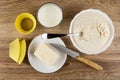 Silicone molds, glass of milk, spoon in bowl with flour mix for muffins, butter in saucer, knife on table. Top view