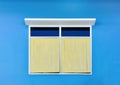 Yellow vintage window with white awning isolated on blue cement wall background Royalty Free Stock Photo