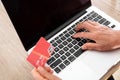 Yellow-skinned middle-aged woman shopping in front of laptop with bank card in hand