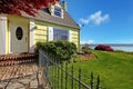 Yellow small classic home with water view and fence.