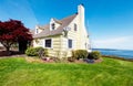 Yellow small home with water view and red maple. Royalty Free Stock Photo