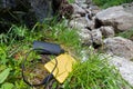 Yellow smartphone charged from a black external battery powerbank, placed on grass, near rocks, up in the mountain