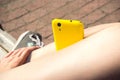 Yellow smartphone on the girl's legs