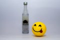 Yellow smiley showing tongue on a white background with a liquor Royalty Free Stock Photo