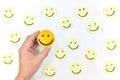 A yellow smiling face icon among a group of happy face emoticons. Positivity, attraction and happiness.