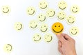 A yellow smiling face icon among a group of happy face emoticons. Positivity, attraction and happiness.