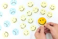 A yellow smiling face icon among a group of sad and happy face emoticons. Positivity, attraction and happiness. Royalty Free Stock Photo