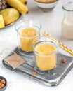 Yellow smoothie in glasses on grey board