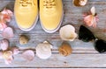 Yellow sneakers ,sunglasses and seashell ,spring  flowers on blue wooden  background ,shoes for women, clothes and footwear access Royalty Free Stock Photo