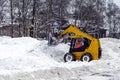 A yellow snow grader cleans snow-covered roads on a city street. concept of snowfall and rainfall. Horizontally, copy space Royalty Free Stock Photo