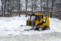 A yellow snow grader cleans snow-covered roads on a city street. concept of snowfall and rainfall. Horizontally, copy space Royalty Free Stock Photo