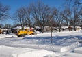 Yellow snow plow truck clearing snow in residential area.