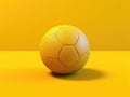 Yellow soccer ball is sitting on bright yellow background. The ball appears to be in center of image, taking up most of