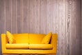 Yellow sofa in front of a wooden wall with copy space background Royalty Free Stock Photo