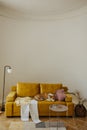 Yellow soft two-seater sofa, small table with additional decor in bright living room. Royalty Free Stock Photo