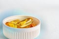 Yellow softgels or capsules are in white bottle cap. Fish oil. Light surface. Vitamins and healthy lifestyle. Bright background Royalty Free Stock Photo