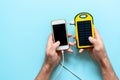 Yellow solar power battery of a device on a blue background in the hands of a man. Royalty Free Stock Photo