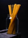 yellow spaghetti macaroni stands in a glass jar on a dark background Royalty Free Stock Photo