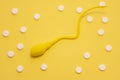 The yellow sperm model is on a yellow polka-dotted background made with white pills. Concept of diagnosis and treatment of male in