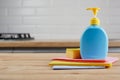 Yellow sponge and blue plastic bottle on wooden table with color cloths, kitchen background Royalty Free Stock Photo