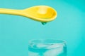Yellow spoon and waterdrop Royalty Free Stock Photo