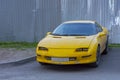 The yellow sports car is real in the courtyard of a residential building with a shabby bumper.