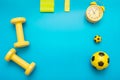 Yellow sports items: dumbbells, balls, elastic bands for sports, alarm clock, on a blue background Royalty Free Stock Photo