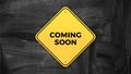 Yellow road sign saying coming soon graphic design on black chalkboard digital background Royalty Free Stock Photo