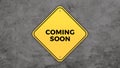 Yellow road sign saying coming soon graphic design on grey cement background Royalty Free Stock Photo