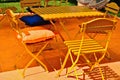 yellow square shaped wooden terrace and restaurant table. foldable wood and metal chairs. patio and terrace Royalty Free Stock Photo