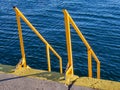 Yellow stairs and handrails on the docks - deep blue sea in the background Royalty Free Stock Photo