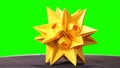 Yellow star origami figurine on green background.