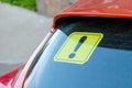 Yellow sticker with an exclamation point on the car`s glass. A newbie driver`s sign