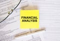 Yellow sticker with text Finansial Analysis on financial docs. Notepad, eyeglasses and white pen Royalty Free Stock Photo