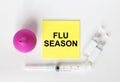 Yellow sticker with text Flu Season on a white background with syringes, enema and ampoule
