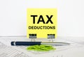 Yellow sticker with text Tax Deductions stands on office clips. Next to it is a blue pen with green paper clips Royalty Free Stock Photo