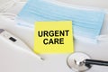 Yellow sticker with text Urgent Care lying with the mask, stethoscope and thermometer