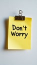 Yellow Sticky Note with Don t Worry Message, Secured by a Black Paperclip on a White Background Royalty Free Stock Photo