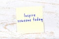 Yellow sticky note with handwritten text inspire someone today