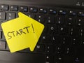 Yellow sticky note with the handwritten word START placed prominently on a black computer keyboard Royalty Free Stock Photo