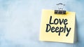 Yellow Sticky Note With Inspiring Message Love Deeply, On A Blue Textured Background. Royalty Free Stock Photo