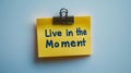 Yellow Sticky Note, Isolated on White, Features Live In The Moment Reminder Written in Blue Marker Royalty Free Stock Photo