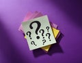 Paper notes with question marks on purple background, flat lay. Space for text Royalty Free Stock Photo