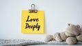 Yellow Sticky Note With Love Deeply Text, Knitted Teddy Bear On A White Background, Love Concept Royalty Free Stock Photo