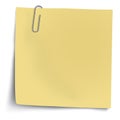 Yellow sticky note with metallic paper clip isolated on white background