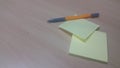 Yellow sticky note paper with pen placed on a wooden table