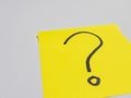 Yellow sticky note with a question mark on a white surface Royalty Free Stock Photo